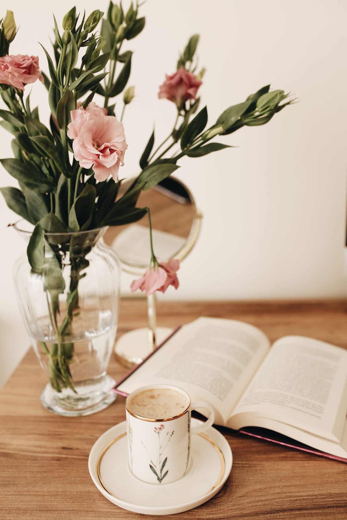 แจกันดอกลิเซียนทัสสีชมพู หนังสือ และกาแฟบนโต๊ะไม้